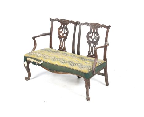 A George III mahogany double chair back settee. The mahogany frame having carved, pierced and interlaced slats, above a seat 