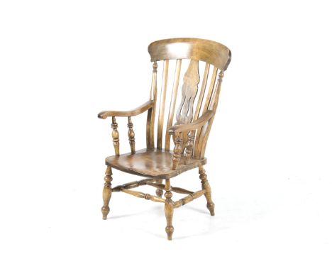 A Victorian oak Windsor armchair. Having a carved central slat, the scroll arms supported by turned supports, raised on bobbi