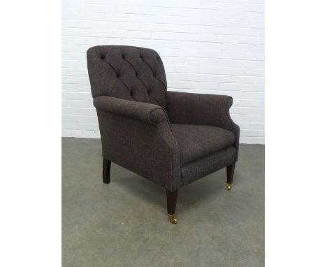 A modern button back armchair, upholstered in dark brown tweed style fabric, on mahogany legs with brass caps and castors, 75