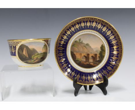 A Barr Worcester teacup and saucer, with topographical scenes against a blue ground and gilt borders,  the saucer painted wit