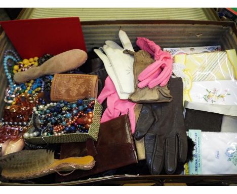 A vintage suitcase containing a collection of vintage costume jewellery, vintage gloves, linen, handerkerchiefs and similar