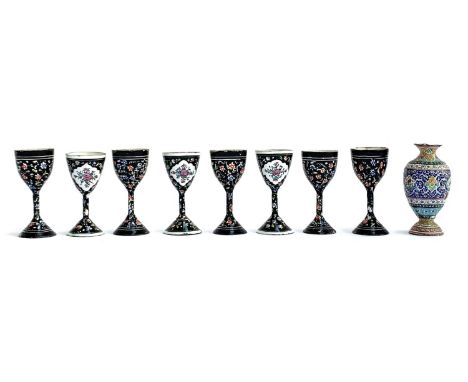 A set of eight Persian minakari enamel small stemmed cups, floral sprays on a black ground, each 9.5cmH; together with a furt