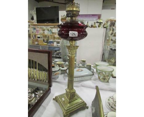 A brass Corinthian oil lamp with ruby glass font (no shade or chimney)