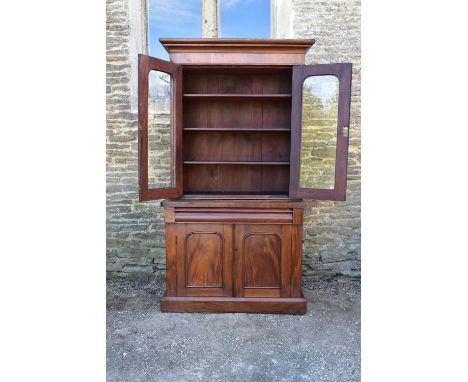 A Victorian mahogany library bookcase with upper glazed section above frieze drawer and panel doors enclosing cellarette draw