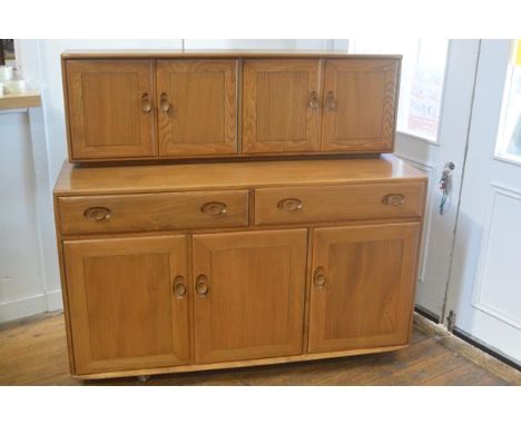 In pristine condition: an Ercol light elm sideboard, the top fitted two pairs of moulded panel doors above two frieze drawers