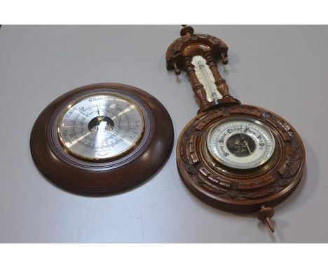 An Edwardian walnut circular aneroid wall barometer complete with thermometer, with carved border and a modern mahogany aneri
