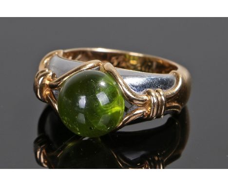 Fine Bulgari peridot ring, the central cabochon peridot at 9.9mm diameter approximately, flanked by yellow metal arched shank