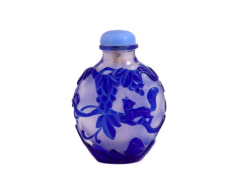 A LARGE BLUE OVERLAY CLEAR GLASS SNUFF BOTTLE Of flattened ovoid shape, well carved with squirrels amongst fruiting vines, 19