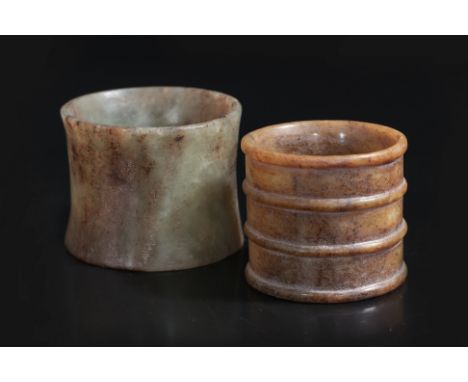 TWO CYLINDRICAL JADE CARVINGS
An archaistic thin green and russet jade carving with waisted sides, and russet jade example wi