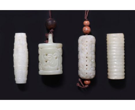 A GROUP OF FOUR CYLINDRICAL CELADON JADE CARVINGS
A bell-form pendant with reticulated stylised dragons to sides, an archaist