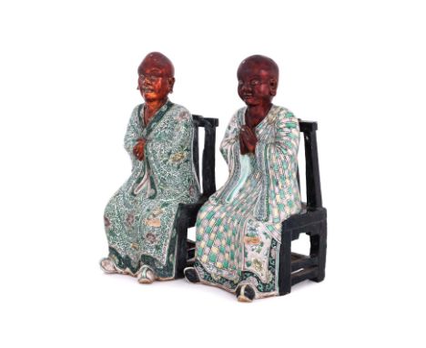 A PAIR OF FAMILLE VERTE BISCUIT PORCELAIN FIGURES OF MONKS
Probably 19th Century, both modelled seated, on a black glazed cha