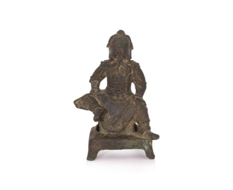 A SEATED BRONZE FIGURE OF GUANDI ON STAND 16th/17th Century, modelled sitting with right leg raised and arms resting on thigh