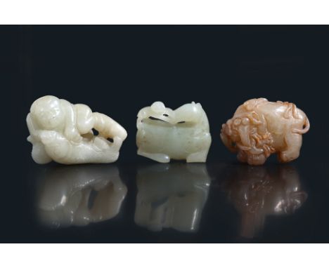 A GROUP OF THREE JADE CARVINGS (2)
An even-toned celadon carving of crouching boy holding a large carp, his foot rested on a 