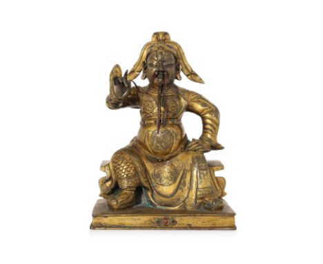 A SEATED GILT-BRONZE FIGURE OF GUANDI Modelled wearing robe over armour, right hand stroking copper beard, seated on rectangu