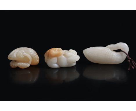 A GROUP OF THREE CARVED JADE ANIMAL PENDANTS
A celadon carved duck facing backwards with head resting over its body, a cealdo