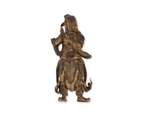 A STANDING GILT BRONZE FIGURE OF GUANDI Ming dynasty, circa 16th/17th century, modelled facing to the side with left arm rais