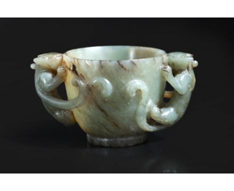 A CARVED JADE CUP
A green and russet jade cup with sides narrowing to a short slightly recessed foot rim, flanked by climbing