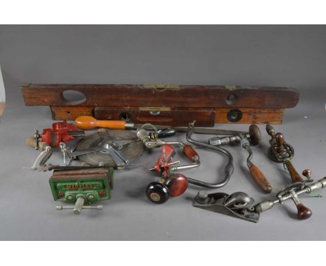 A collection of assorted antique tools, including wood and brass spirit levels, the largest 104cm in length, hand drills, cla