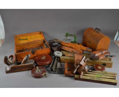 A collection of assorted antique tools, including wooden and brass spirit levels, of differing sizes, tape measures, plains, 