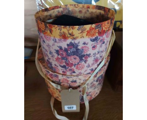 Two floral decorated hat boxes containing three vintage hats, two fez and a 1920's style lady's hat