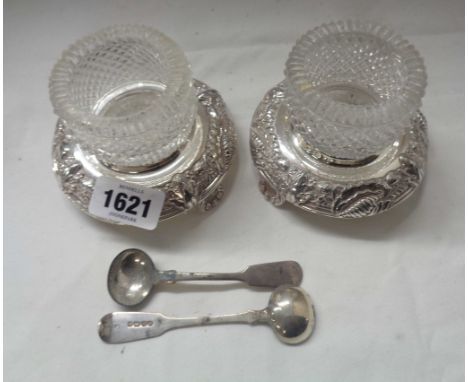 A pair of large hobnail cut glass table salts with associated silver spoons, set on ornate silver plated bases