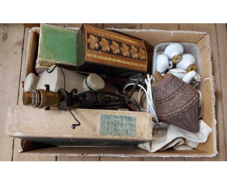 A box containing a small wrought iron table lamp, stoneware hot water bottle, ceramic doorknobs, etc.