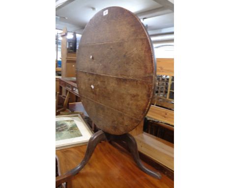 A 75cm diameter antique oak tilt-top table, set on turned pillar and tripod base