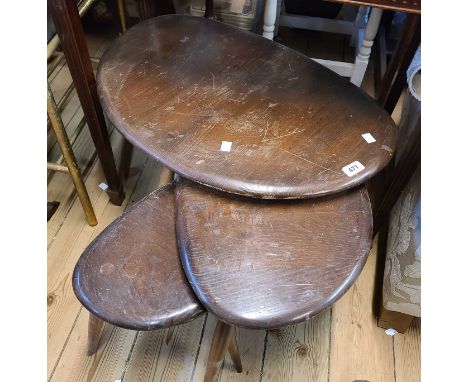 A vintage Ercol dark elm nest of three 'Pebble' tea tables, set on simple turned supports