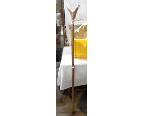 A tall walking stick with a horn handle and integral carved whistle