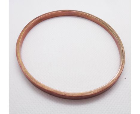 A 375 (9ct.) rose gold bangle with engine turned finish