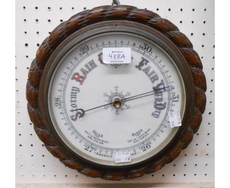 A late Victorian oak framed aneroid wall barometer with rope twist border and printed ceramic dial - splits