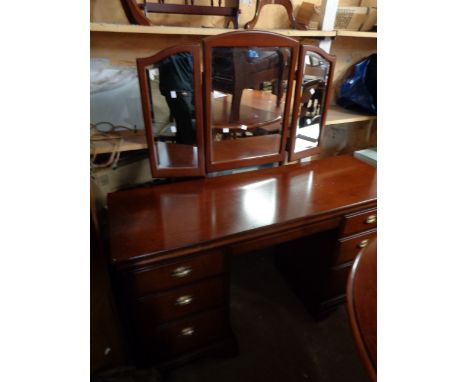 A 1.34m Stag mahogany kneehole dressing table with triple mirror over blind frieze drawer and six flanking pedestal drawers, 