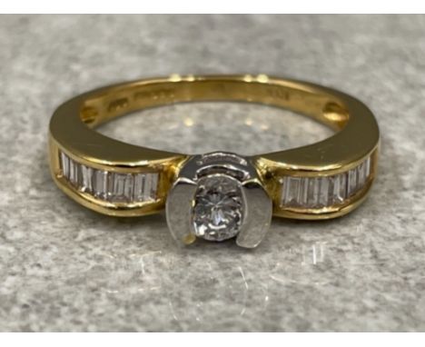 Ladies 18ct gold Diamond ring. Featuring a round brilliant cut diamond in centre and shoulders set with Baguettes. 4.73g size