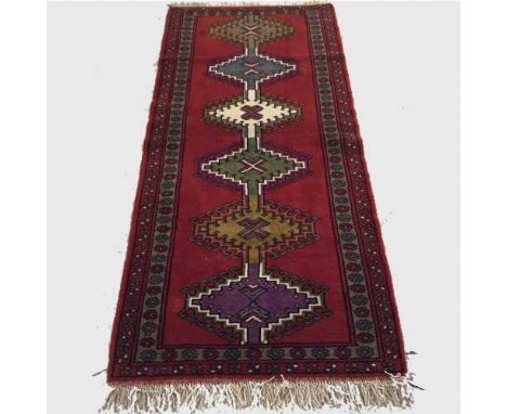A wool Eastern carpet runner on red ground, 191 cm x 85 cm.