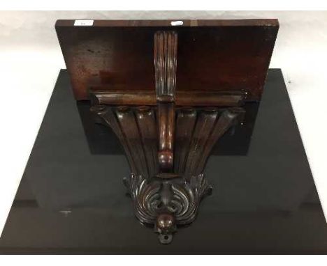 A mid nineteenth century mahogany wall bracket, the back carved with seven plumes , the table veneered and supported by a rec