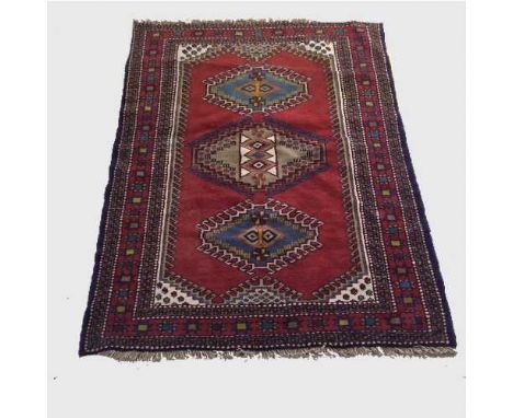 A wool Eastern carpet on red ground medallion central panel, 172 cm x 124 cm.