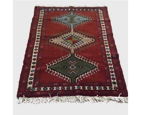 A wool Eastern carpet on red ground with geometric patterns, 170 cm x 122 cm.