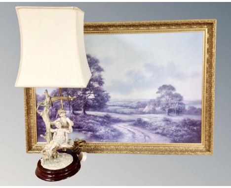 A gilt framed landscape print together with a continental table lamp.