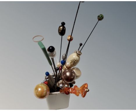 A ceramic pot containing antique and vintage hat pins.