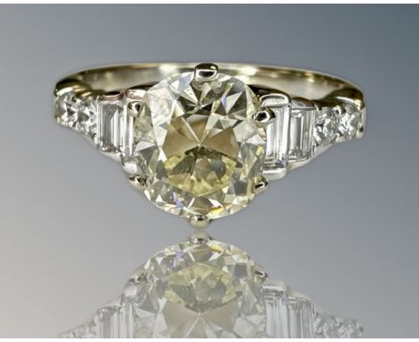 An 18ct yellow gold diamond ring, the central old cut stone approximately 1.5ct set with emerald and round cut diamond should