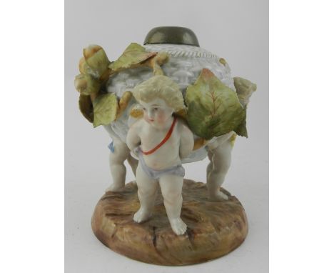 A Dresden porcelain figural oil lamp fashioned as a basket, supported by amorini, early 20th century. H.16cm