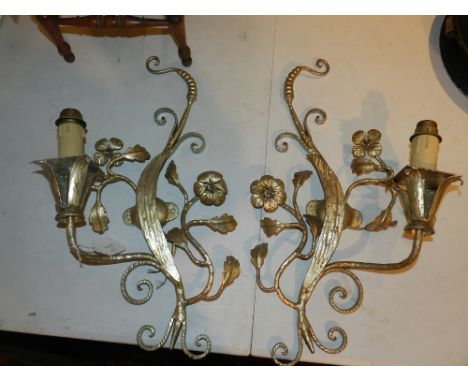 A pair of silvered metal-work wall lights, shaped as scrolling leaves with floral adornment, supporting a single light above 