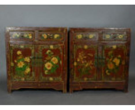 A pair of Chinese scarlet lacquered cabinets, floral painted and fitted with two short frieze drawers above two cupboard door