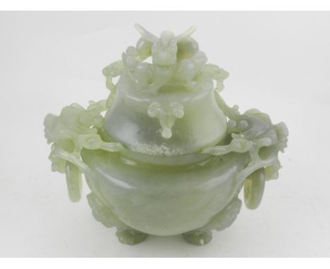 A Chinese carved and pierced celadon jadeite koro and cover, having twin dragon mask handles below a dragon finial, raised on