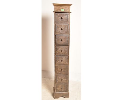 A vintage 20th century carved hardwood upright chest of drawers having flared tops flanked vertically by a carved frieze over