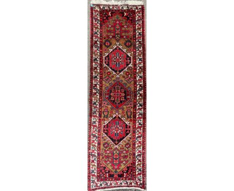 A mid 20th Century Persian / Islamic heriz rug / carpet runner. The rug hand knotted with natural wool colours, three diamond