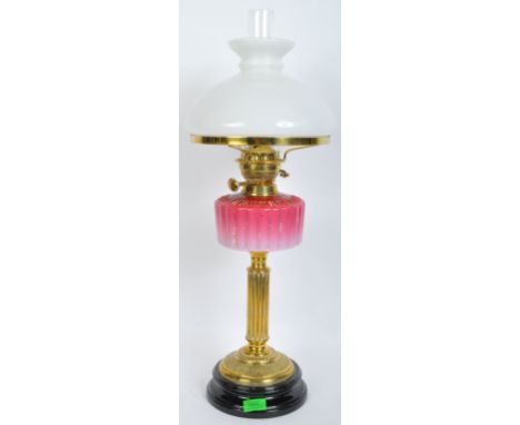 A Victorian oil lamp with brass Corinthian column stand and opaque pink glass reservoir with chimney and large opaque white g