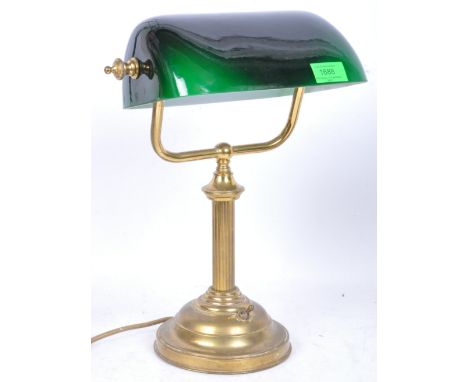 An early 20th century circa. 1920's bankers lamp having a green glass rectangular shade over a brass base with reeded columna