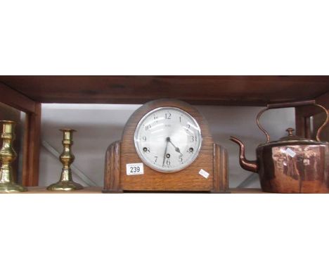 A mantle clock, a copper kettle and a pair of brass candlesticks.