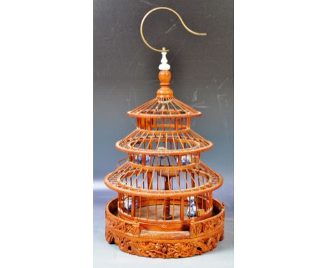 An antique early 20th Century Chinese carved bamboo birdcage having a brass hanging hood with ivory finial, slatted sides wit